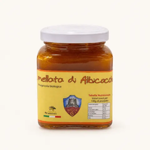 Square glass jar of apricot jam with yellow label featuring red text and Felice Agricoltura logo, white screw cap, nutritional information and product name visible.